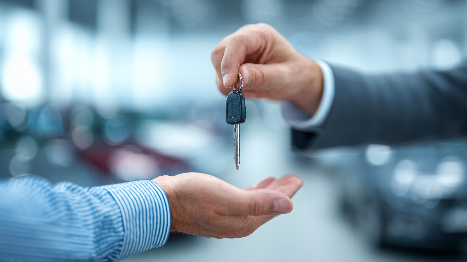 Nahaufnahme des Autohausleiters bei der Übergabe der Autoschlüssel an einen Kunden in einem Ausstellungsraum, Konzept für Fahrzeugkauf, Autoverkauf und -vermietung